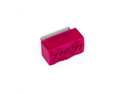 Small pink 3D-printed rectangular block with 'STL' embossed on the side and a metal insert visible inside.