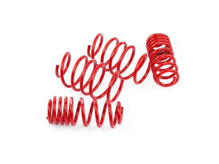 Three glossy red metal springs lying on a white background on the surface at different angles.